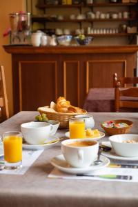 una mesa con tazas y platos de comida y zumo de naranja en Hôtel du Ladhof en Colmar