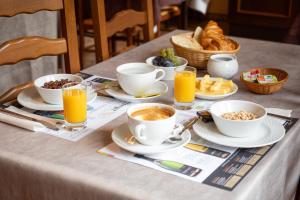 a table topped with cups of coffee and breakfast foods at H&ocirc;tel du Ladhof in Colmar