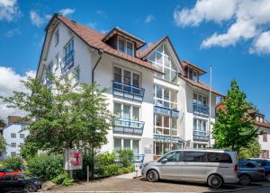 ein weißes Gebäude mit blauen Balkonen und einem Van vor dem Haus in der Unterkunft Garni-Hotel Sailer & Hotel Sailer´s Villa in Rottweil