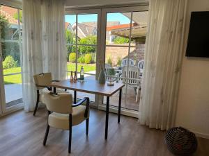 a dining room with a table and chairs and windows at Appartement Gartenglück in Nordhorn