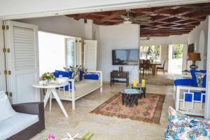 un soggiorno con mobili bianchi e blu e un tavolo di Villa en Barú con playa privada 6BR a Barú