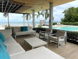 un patio con muebles blancos y una piscina en Villa en Barú con playa privada 6BR, en Barú