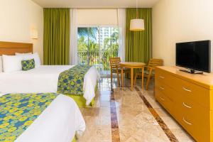 um quarto de hotel com duas camas e uma televisão de ecrã plano em Krystal Vallarta em Puerto Vallarta