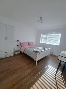 a white bedroom with a bed and a desk at GATWICK HOUSE in Crawley