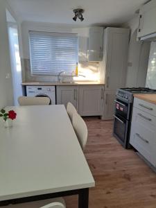 uma cozinha com armários brancos e uma mesa com cadeiras em GATWICK HOUSE em Crawley
