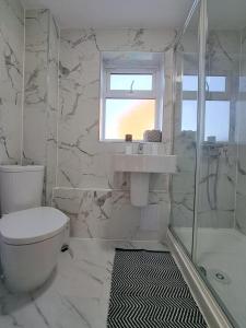 baño con aseo y lavabo y ventana en GATWICK HOUSE, en Crawley