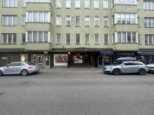 tres coches estacionados frente a un gran edificio en Cosy City Central Flat with self check-in, en Helsinki