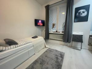 1 dormitorio con 1 cama, TV y ventana en Cosy City Central Flat with self check-in, en Helsinki