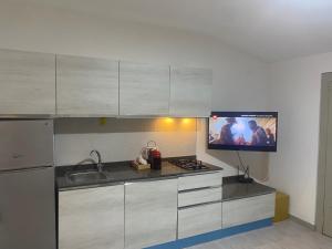 een keuken met een wastafel en een tv aan de muur bij Casa vacanza Nicole in Caltagirone