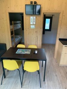 a dining room with a table and yellow chairs at Càmping Organyà Park in Organyà