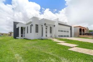 uma casa branca com um relvado verde em Casa Catalina - 11 min from BQN em Aguacate