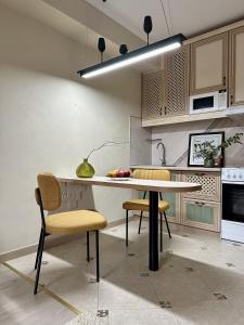 a kitchen with a table and chairs in a room at Студия ПЕНИЕ ПТИЦ в центре Алматы in Almaty +8 photos