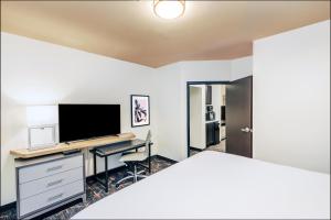 a bedroom with a bed and a desk with a television at Holiday Inn & Suites Stillwater-University West, an IHG Hotel in Stillwater