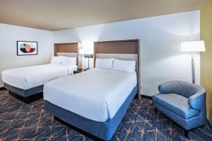 Holiday Inn & Suites Stillwater-University West, an IHG Hotel في ستيلووتر: غرفة فندقية بسريرين وكرسي