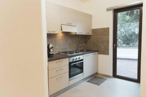 a kitchen with white cabinets and a stove top oven at Cas'aPina apartment in Aci Bonaccorsi