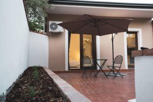 a patio with a table and chairs and an umbrella at Cas'aPina apartment in Aci Bonaccorsi
