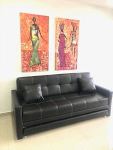 a black couch in a room with two paintings on the wall at Apartamento Buenaventura in Buenaventura