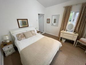 a bedroom with a white bed and a mirror at Little Owl Cottage in Faversham