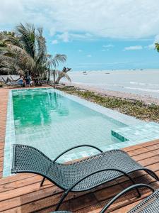 a swimming pool with a bench next to a beach at Pousada Boa Sorte in Cumuruxatiba