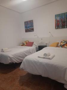 two beds in a room with white sheets at Mi casa de Molina in Molina de Segura