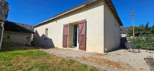 a small white building with red doors on it at Maison de village in Sadroc