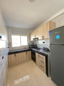 a kitchen with wooden cabinets and a stainless steel refrigerator at Lovely 2 bedroom apartment in Rabat +4 photos