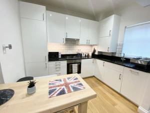 a kitchen with white cabinets and a table with a flag on it at 2 Bedroom Flat in Whitechapel! in London