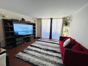 a living room with a red couch and a flat screen tv at Departamento Lujo 3A 2B Borde Rio in Calama