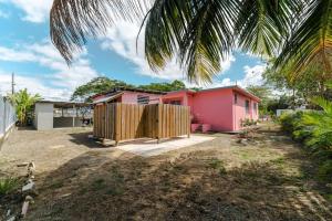 una casa rosa con una valla de madera en un patio en Coral Casa just one block from the beach, en Stella