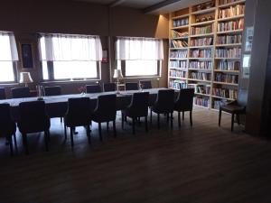 une bibliothèque avec une longue table, des chaises et des étagères dans l'établissement Ellivuori, Ellin Pooli2, à Sastamala