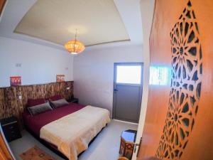a bedroom with a large bed and a window at Atlantic Vibes Surf Hostel in Tamraght Ouzdar