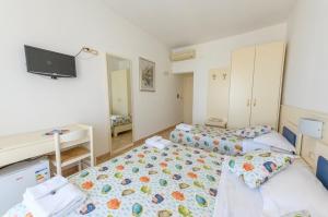 1 dormitorio con 2 camas, escritorio y TV en B&B Anna Lungomare, en Agropoli