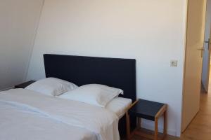 a white bed with a black headboard and a table at Katwijk Center, 1 min away from the beach! in Katwijk aan Zee