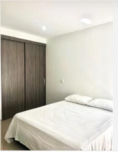 a bedroom with a white bed with a wooden cabinet at Apartamento Buenaventura in Buenaventura