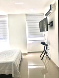 1 dormitorio con 1 cama, TV y silla en Apartamento Buenaventura, en Buenaventura
