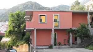 una casa roja con montañas en el fondo en Lero Apartments, en Budva