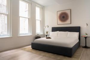 a bedroom with a bed with white sheets and windows at Sonder The Witherspoon in Philadelphia