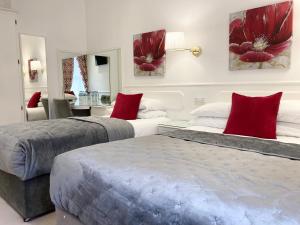 two beds in a room with red pillows at Dergvale Hotel in Dublin