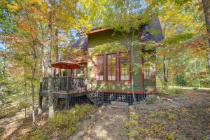 a green house with a deck in the woods at WNC French Broad RiverWalk Retreat with WiFi in Hot Springs