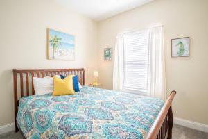 um quarto com uma cama com uma colcha colorida e uma janela em A Kure for the Sol em Kure Beach
