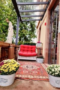 eine rote Couch auf einer Veranda mit Blumen in der Unterkunft Hôtel Le Manoir in Barr