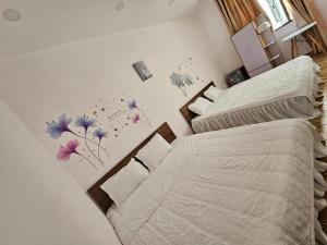 a bedroom with two beds and flowers on the wall at Homestay ánh chi in Phú Quốc