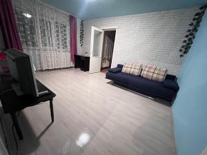 Comfycondo apartment في زالاو: غرفة معيشة مع أريكة زرقاء وتلفزيون