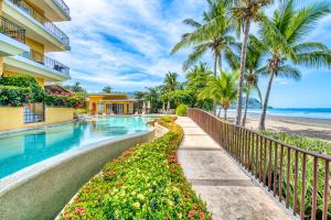un complejo con piscina con palmeras y playa en SecretJaco - Luxury Beach Front Penthouse with Pool & Jacuzzi, en Jacó