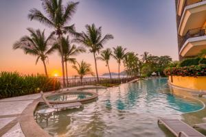 una piscina con palmeras y un edificio en SecretJaco - Luxury Beach Front Penthouse with Pool & Jacuzzi, en Jacó