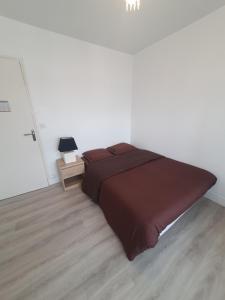 ein großes Bett in einem weißen Zimmer mit Holzboden in der Unterkunft Appartement Gien in Gien