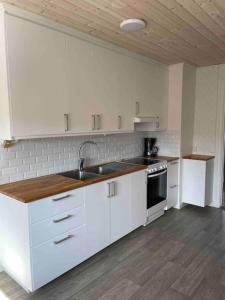 Una cocina con gabinetes blancos y un fregadero. en Brewer by MoraTomten, en Mora
