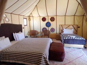 a room with two beds in a tent at SAHARA WAVES CAMP in Merzouga