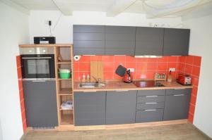 a small kitchen with gray cabinets and orange tiles at Ferienwohnung Uckermarkblick in Ziehten