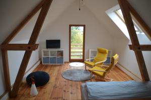 a attic room with a bed and two yellow chairs at Ferienwohnung Uckermarkblick in Ziehten